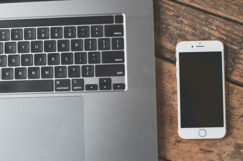 A sleek laptop and smartphone on a wooden table, showcasing modern technology essentials.